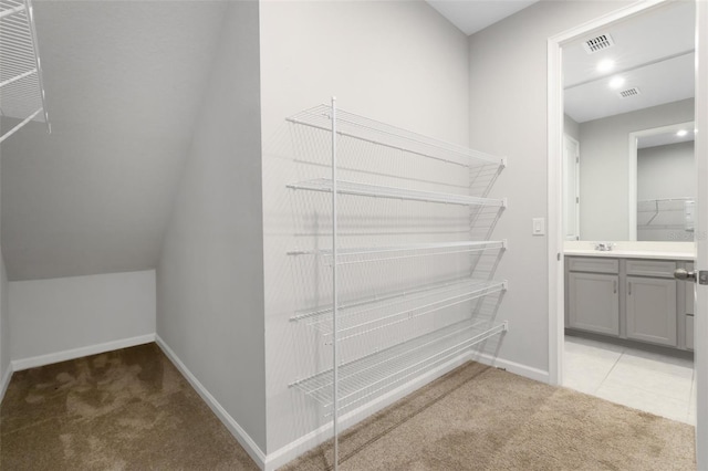 walk in closet with light carpet, a sink, and visible vents