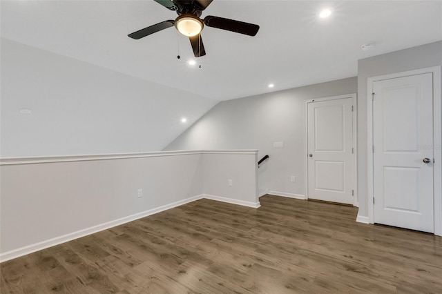 additional living space with vaulted ceiling, dark wood-type flooring, a ceiling fan, and baseboards