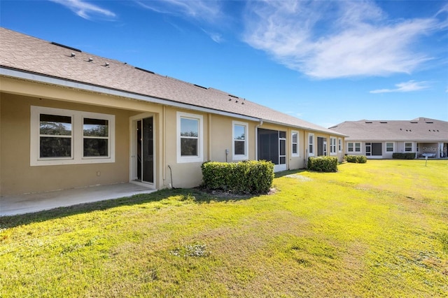 rear view of house featuring a yard, roof with shingles, a patio area, and stucco siding