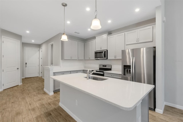 kitchen featuring appliances with stainless steel finishes, light countertops, and a center island with sink