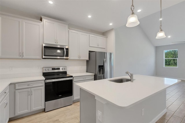 kitchen featuring stainless steel appliances, a sink, light countertops, an island with sink, and decorative light fixtures