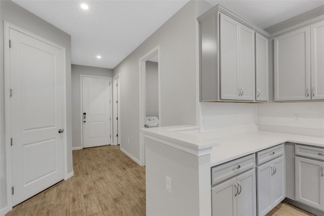 kitchen with light wood-type flooring, a peninsula, and light countertops