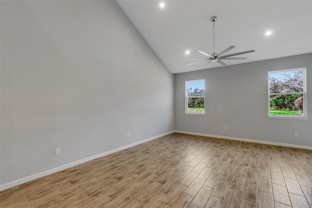 empty room featuring a ceiling fan, vaulted ceiling, light wood-style flooring, and baseboards