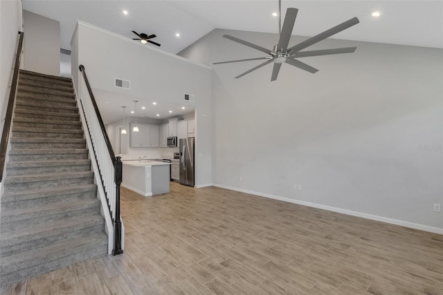 unfurnished living room featuring visible vents, ceiling fan, light wood-style flooring, and stairs