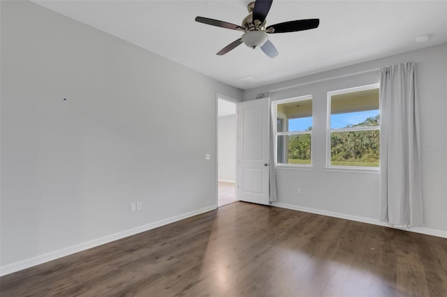 unfurnished room featuring dark wood-style flooring, ceiling fan, and baseboards