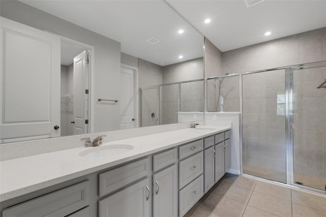 full bathroom with a stall shower, tile patterned floors, a sink, and double vanity