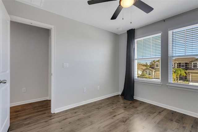 empty room featuring dark wood-style floors, baseboards, and a ceiling fan