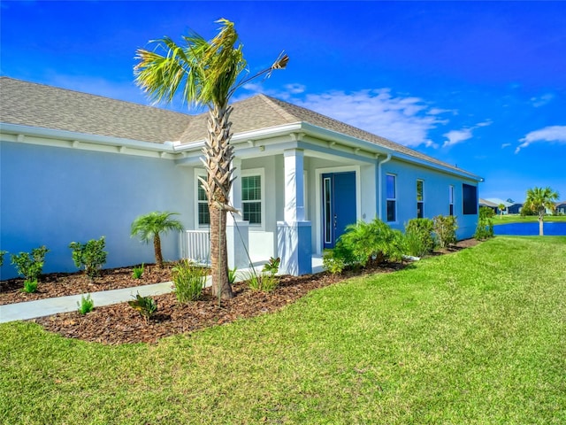 view of side of property featuring roof with shingles, a lawn, and stucco siding