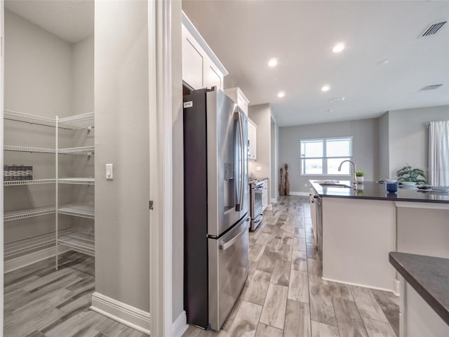 kitchen featuring appliances with stainless steel finishes, dark countertops, white cabinets, and a sink