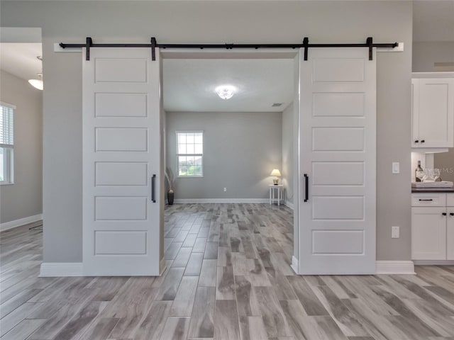 kitchen featuring a barn door, white cabinetry, and light wood-style floors