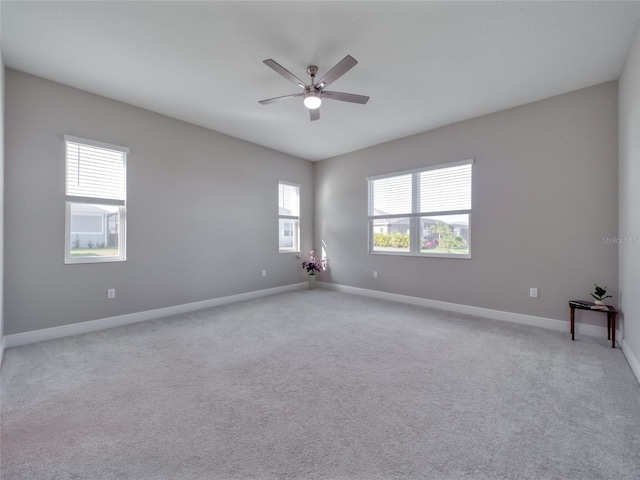 empty room with ceiling fan, light colored carpet, and baseboards