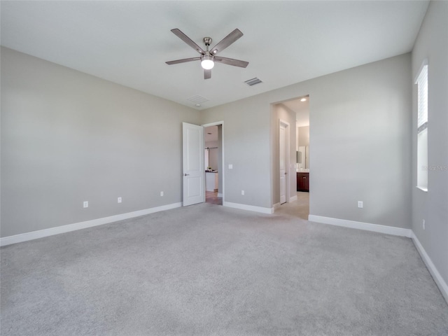 empty room featuring light colored carpet, visible vents, ceiling fan, and baseboards