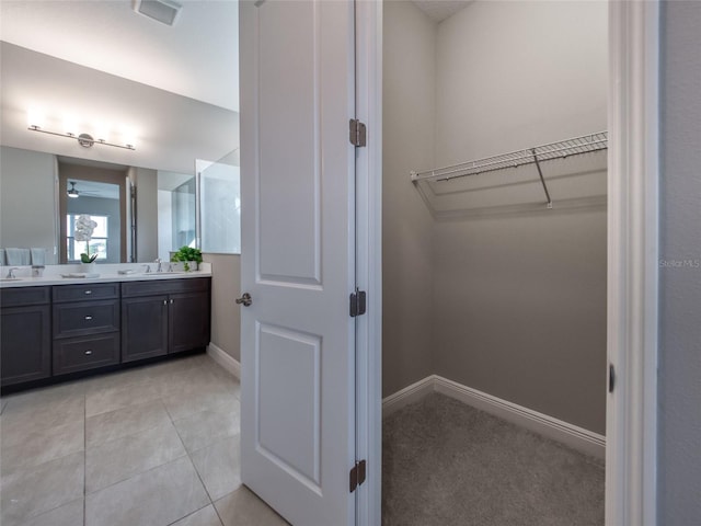 bathroom featuring a sink, visible vents, baseboards, tile patterned floors, and double vanity