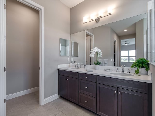 bathroom featuring tile patterned flooring, a sink, baseboards, and double vanity