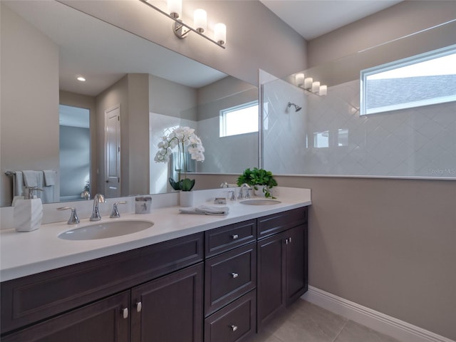 full bath featuring baseboards, double vanity, a sink, and tile patterned floors