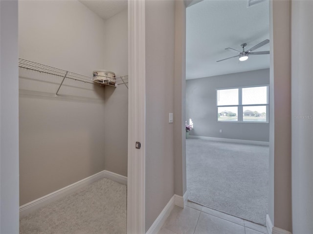 spacious closet with a ceiling fan, light carpet, and light tile patterned flooring