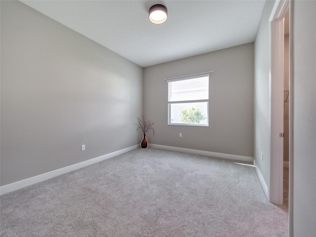 unfurnished room featuring baseboards and light colored carpet