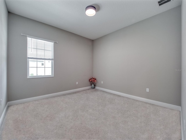 unfurnished room with baseboards, visible vents, and light colored carpet