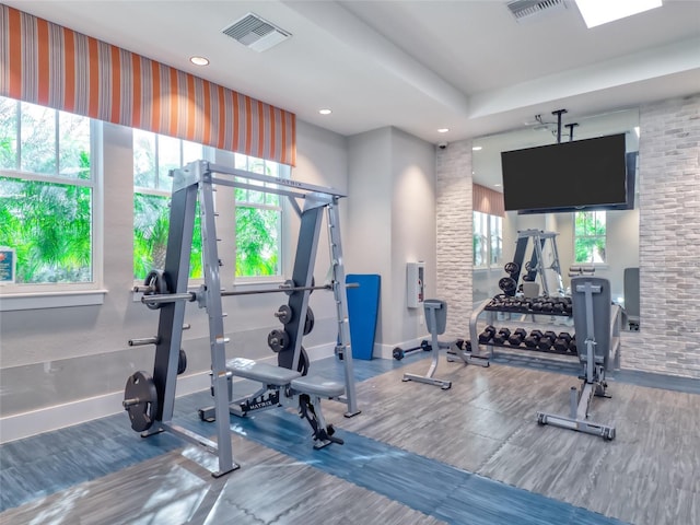 workout area featuring baseboards, visible vents, and wood finished floors