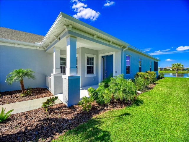 view of side of property featuring a water view, a yard, and stucco siding