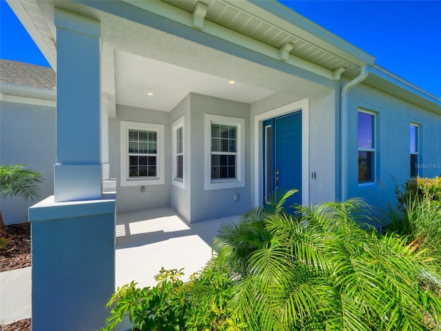 view of exterior entry featuring a patio area and stucco siding