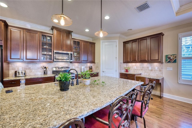 kitchen with crown molding, sink, hanging light fixtures, light stone countertops, and appliances with stainless steel finishes