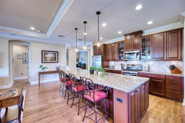 kitchen with ornamental molding, a breakfast bar, stainless steel appliances, pendant lighting, and a center island