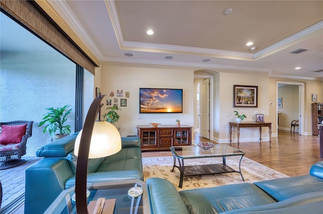 living room featuring hardwood / wood-style floors, a tray ceiling, and ornamental molding