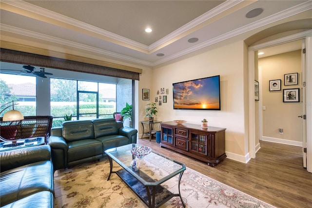 living room with wood-type flooring, a tray ceiling, ceiling fan, and crown molding