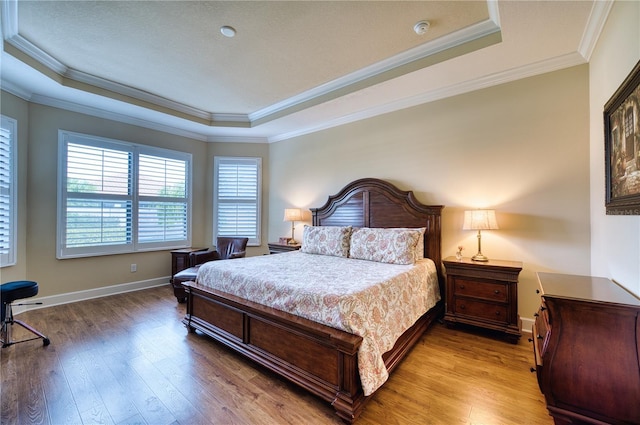 bedroom featuring hardwood / wood-style floors, ornamental molding, and a tray ceiling