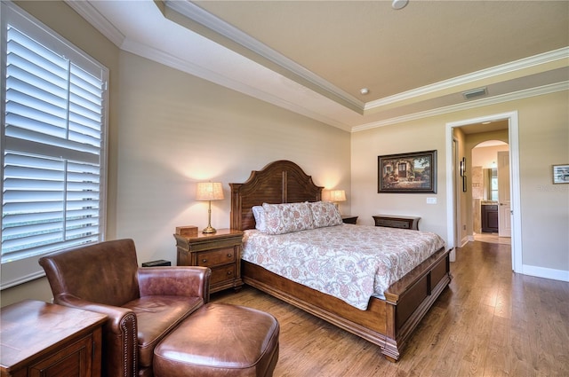 bedroom featuring hardwood / wood-style flooring, a raised ceiling, and crown molding