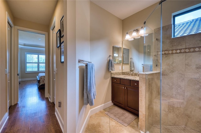 bathroom with vanity, a tile shower, and wood-type flooring