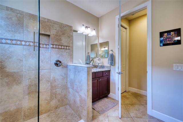 bathroom featuring a tile shower, vanity, and tile patterned floors