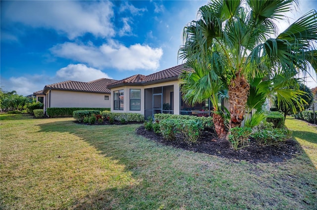 view of side of home featuring a lawn and a sunroom