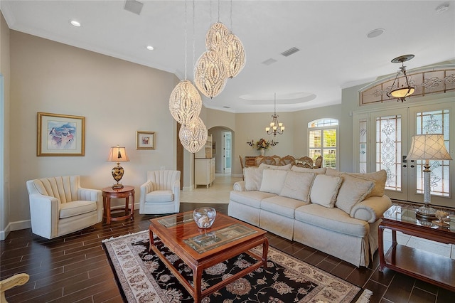 living room featuring french doors, ornamental molding, and an inviting chandelier