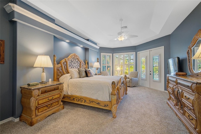 carpeted bedroom featuring access to exterior, a tray ceiling, and ceiling fan