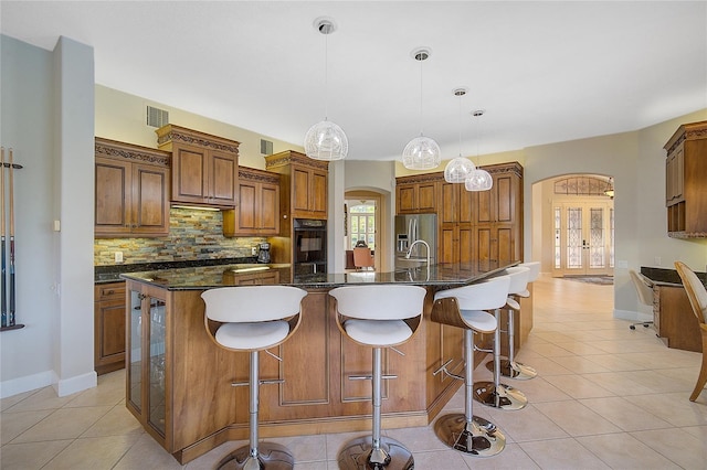 kitchen featuring a large island, stainless steel fridge with ice dispenser, backsplash, pendant lighting, and light tile patterned flooring