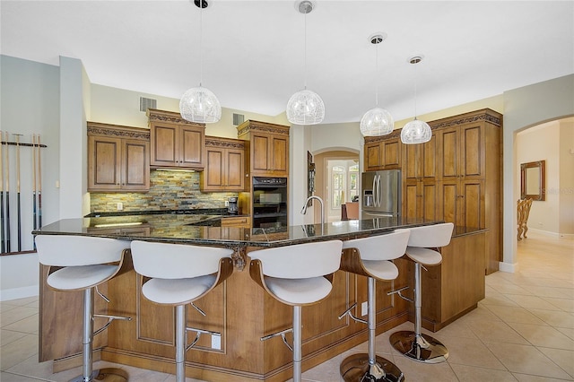 kitchen featuring a large island, hanging light fixtures, stainless steel refrigerator with ice dispenser, decorative backsplash, and a breakfast bar