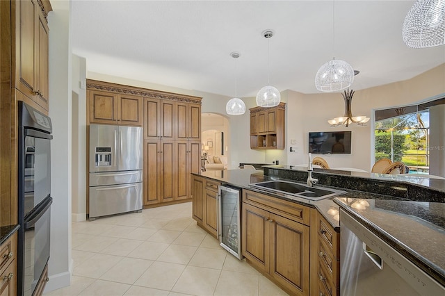 kitchen with sink, stainless steel appliances, wine cooler, a chandelier, and pendant lighting