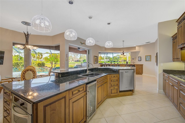 kitchen with pendant lighting, sink, an island with sink, appliances with stainless steel finishes, and beverage cooler