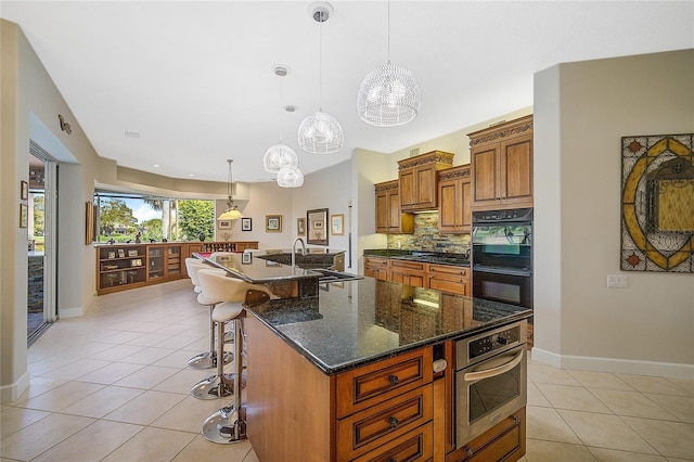 kitchen featuring a kitchen breakfast bar, black double oven, a spacious island, sink, and pendant lighting