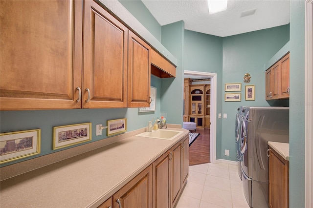 laundry room with washer and clothes dryer, cabinets, sink, light tile patterned floors, and a textured ceiling