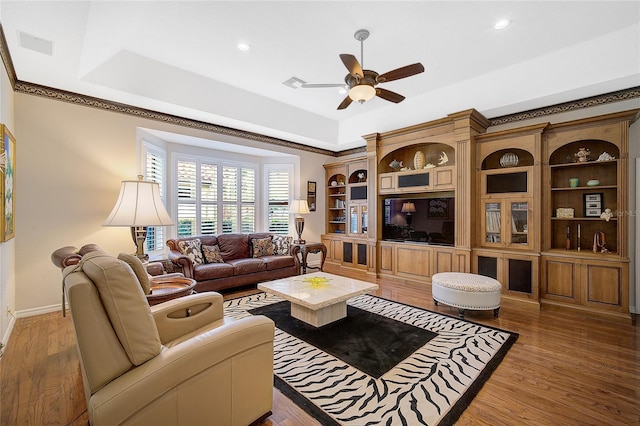 living room with a tray ceiling, ceiling fan, and hardwood / wood-style floors