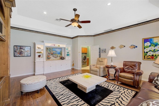 living room with ceiling fan, ornamental molding, wood-type flooring, and washer / dryer