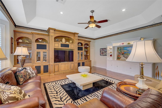 living room with a raised ceiling and ceiling fan