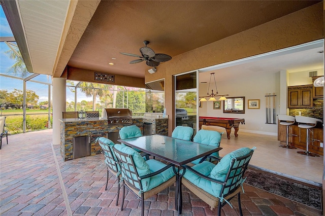 view of patio / terrace with grilling area, glass enclosure, ceiling fan, and exterior kitchen