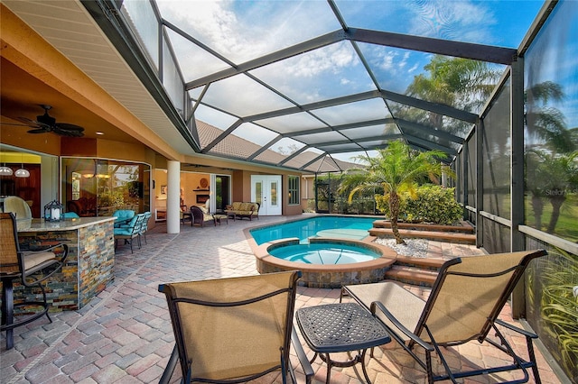 view of pool featuring an in ground hot tub, a lanai, exterior bar, ceiling fan, and a patio