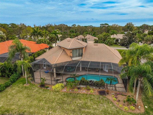 back of property with a yard and glass enclosure