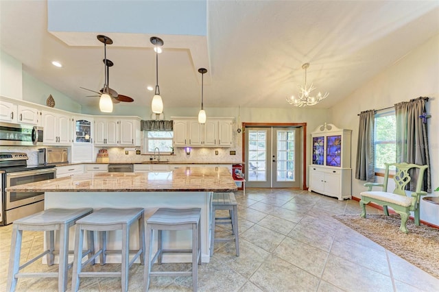 kitchen featuring white cabinets, tasteful backsplash, decorative light fixtures, a kitchen island, and stainless steel appliances