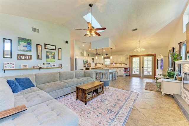 living room featuring french doors, high vaulted ceiling, a fireplace, light tile patterned flooring, and ceiling fan with notable chandelier